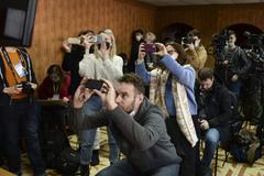 Journalists take pictures from a TV monitor showing Russian opposition leader Alexei Navalny speaking via a video link during a court session.