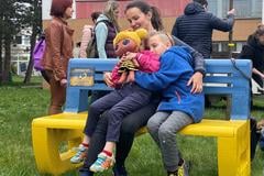 На фото — українська родина сидить на лавці в кольорах українського прапора з нагоди Дня Землі у місті Prievidza, квітень 2022 року.