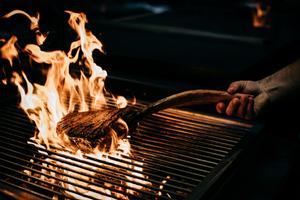 Preparing a tomahawk steak, an on-the bone rib steak, on the new coal-fired grill.