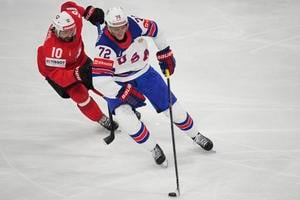 Švajčiarsky hráč Andres Ambuhl(vľavo) bojuje o puk s Američanom Michaelom Kesselringom vo finále Švajčiarsko - USA na MS 2025 v hokeji.
