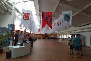 A spacious entrance hall decorated with flags, evoking the atmosphere of a medieval knight’s hall.