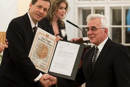 Ivan Kolenka (right) accepts a certificate on behalf of his uncle Vojtech from Isaak Herzog.