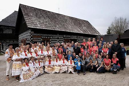 Athletes and local people pose next to buildings bearing typical Čičmany decorations.