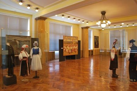 Paintings mix with authentic folk costumes in museum's big hall.