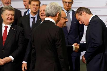 British PM David Cameron (R) shakes hands with French President Francois Hollande at Eastern Partnership summit. Front row left is Ukrainian President Petro Poroshenko, next to him Slovak president Kiska.  