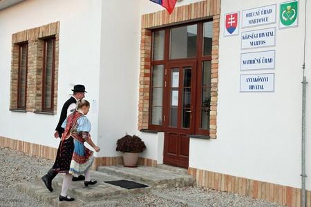 A couple wearing traditional Slovak clothes enter a town hall in Martovce, Nitra Region, to cast their ballot in the 2018 municipal election.