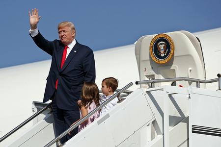 Trump waves as he walks down the steps of Air Force One with his grandchildren after arriving at Morristown Municipal Airport to begin his summer vacation at his Bedminster golf club in Morristown, N.J. 