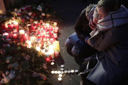 Two women mourn beside candles in Berlin, Germany, the day after a truck ran into a crowded Christmas market nearby and killed several people.
