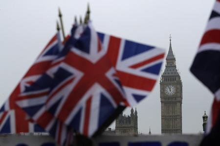 Flags displayed on a tourist stall, backdropped by the Houses of Parliament and Elizabeth Tower containing the bell know as Big Ben, in London.