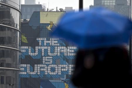 A man walks with an umbrella outside EU headquarters in Brussels.
