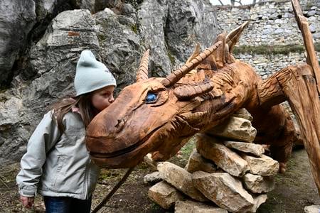 Na Beckovský hrad “priletel” drak, ktorému dali meno Blundus. Podľa legendy v hradnej studni kedysi jeden žil a miestnych obyvateľov budil hlasným chrápaním. Viac ako 6-metrový drevený drak sa stal novou exteriérovou atrakciou. Na snímke dievčatko bozkáva draka Blundusa. Beckov, 27. februára 2020. FOTO TASR - Radovan Stoklasa