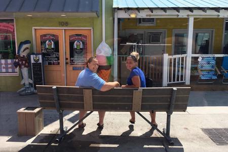 Two women sit on a bench opposite an ice-cream parlour in Carolina Beach, North Carolina, USA.