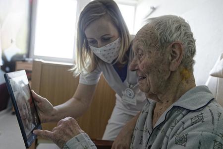 A 99-year-old man communicates with his grandchild via a video call on April 28, 2020.