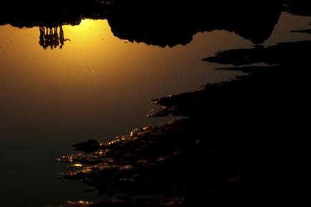 Tourists reflected in the sea at sunset at Makronissos beach in the southeast resort of Ayia Napa on the eastern Mediterranean island of Cyprus.