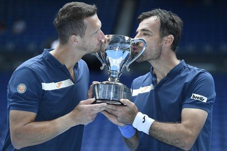 Slovakia's Filip Polasek (left) and Croatia's Ivan Dodig kiss their trophy after defeating Rajeev Ram of the US and Britain's Joe Salisbury in the men's doubles final at the Australian Open tennis championship in Melbourne, Australia, Sunday, Feb. 21, 2021.
