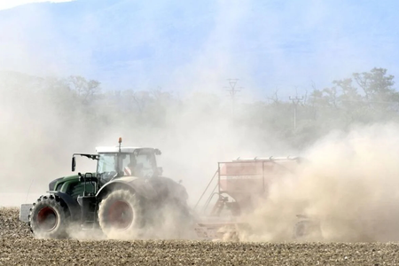 A tractor towing a seeder.