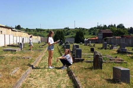 Spišská Nová Ves students are waiting for visitors to come to the Jewish cemetery in the town at the end of June 2021.