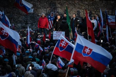 Robert Fico addressed the crowd protesting against DCA, standing against a backdrop of far-right ĽSNS flag. 