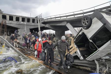 People cross an improvised path under a destroyed bridge while fleeing the town of Irpin close to Kyiv, Ukraine, on March 7.