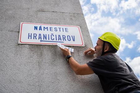 Martin Bednárik installing a magnet bearing the word "victims" on the Námestie Hraničiarov square name sign.
