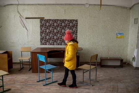 A Ukrainian girl poses in a destroyed classroom.