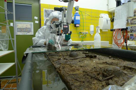 Work in the laboratory on a board from the floor of the tomb. In the foreground, parts of wooden furniture can be seen.