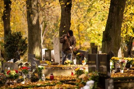 A man clears the grave of his loved ones of autumn leaves during All Saints' Day at the National Cemetery in Martin on Wednesday, 1 November 2023.