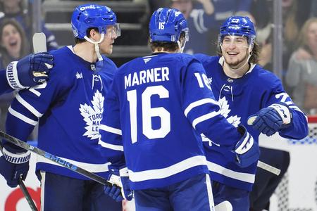 Hráč Toronto Maple Leafs Mitch Marner (uprostred) oslavuje so spoluhráčmi Jakeom McCabeom (vľavo) a Matthewom Kniesom (23).