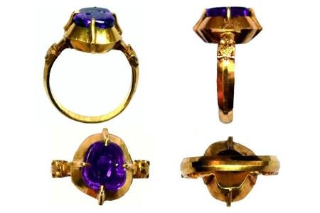 A striking 18-carat gold ring adorned with a deep red-purple sapphire