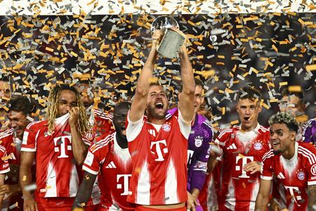 Hráč Bayernu Harry Kane (uprostred) oslavuje s trofejou po víťazstve vo finále zápasu Nemeckého superpohára VfB Stuttgart - Bayern Mníchov.