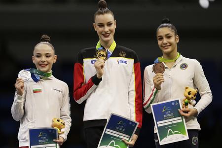 Nemecká reprezentantka v modernej gymnastike Darja Varfolomejevová (uprostred) pózuje na pódiu so zlatou medailou po triumfe vo finále viacboja jednotlivkýň na majstrovstvách sveta v brazílskom Riu de Janeiro v piatok 22. augusta 2025. Druhá skončila Bulharka Stiliana Nikolovová (vľavo) a bronz získala päťnásobná majsterka sveta Sofia Raffaeliová z Talianska.