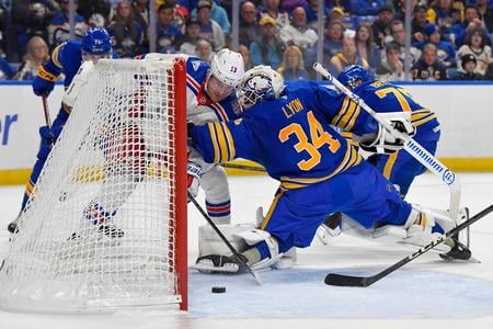 Útočník New York Rangers Alexis Lafreniere (vľavo) strieľa gól do siete brankára Buffalo Sabres Alexa Lyona.