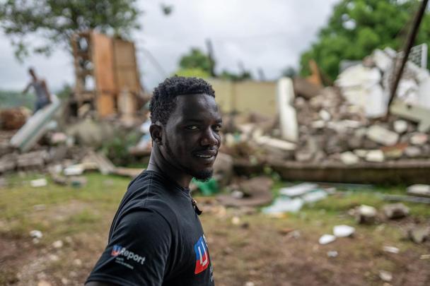 Wadelet stojí pred zrútenou budovou v Pestel, Haiti