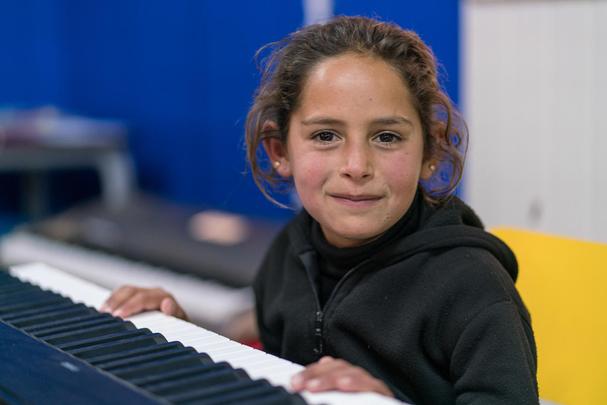 7-ročná Alaa hrá na klavír počas hudobného terapeutického programu UNICEF “Musiqati” v utečeneckom tábore Azraq v Jordánsku. Hodiny hudby pomáhajú deťom sýrskych utečencov vyliečiť rany na duši, prekonať spôsobené traumy a nájsť spôsob, ako vyjadriť svoje pocity. “O tomto mieste mi povedali moji kamaráti,” hovorí Alaa. “Povedali mi, že je tam hudba, hra a všeličo ostatné. Veľmi sa mi to páči, pretože hudba je pre mňa všetkým. Najradšej mám hru na klavír.”