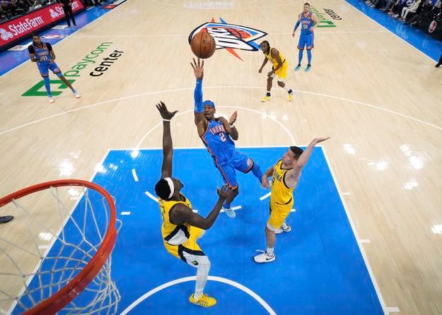 Thunder Shai Gilgeous-Alexander (uprostred) strieľa na kôš cez Pascala Siakama (43) a T.J. McConnella (9) z Indiany Pacers v 2. zápase finále play off zámorskej basketbalovej NBA v Oklahoma City.