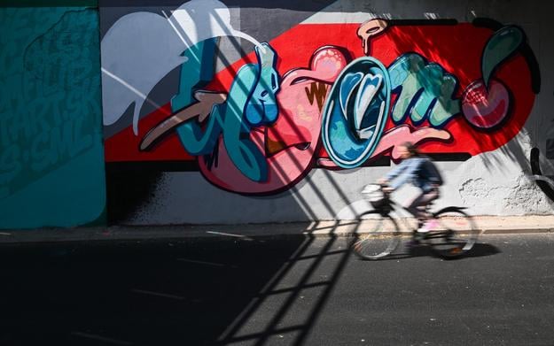 A cyclist passing by a new graffiti created during the Fest Art 2025 event in Trenčín on June 20.
