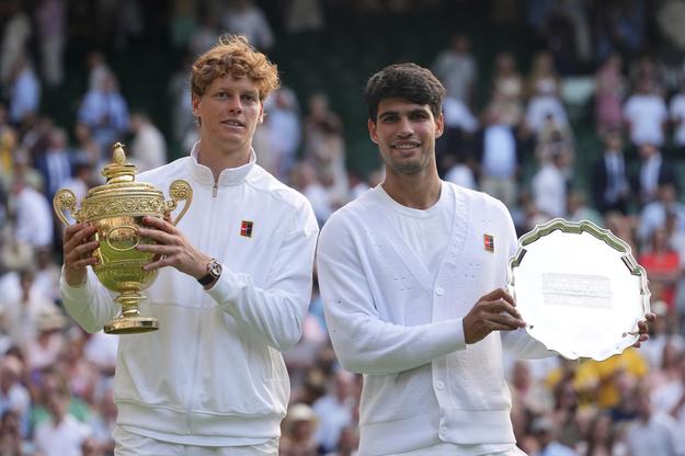 Taliansky tenista Jannik Sinner (vľavo) pózuje s trofejou po víťazstve nad Španielom Carlosom Alcarazom (vpravo) vo finále mužskej dvojhry na grandslamovom turnaji vo Wimbledone.