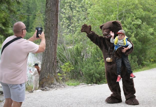 Tourists with a man in a bear costume at Štrbské Pleso in the High Tatras on 19 July 2025.