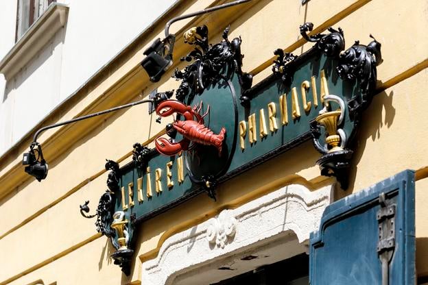 Following repairs, the iconic shield of the Lekáreň u Červeného Raka pharmacy has been reinstalled on its original façade in Bratislava’s city centre.
The damaged emblem, depicting a red crayfish, had been on display inside the pharmacy’s visitor centre for several months. According to the Bratislava City Museum, which manages the historic site, the crayfish is a traditional symbol of healing. Medieval manuscripts even refer to its use in medicine.