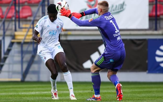 Brankár Dominik Ťapaj vyráža loptu spred hlavy slovanistu Sharaniho Zuberu. Zo stretnutia Ružomberok - Slovan vo februári 2025.