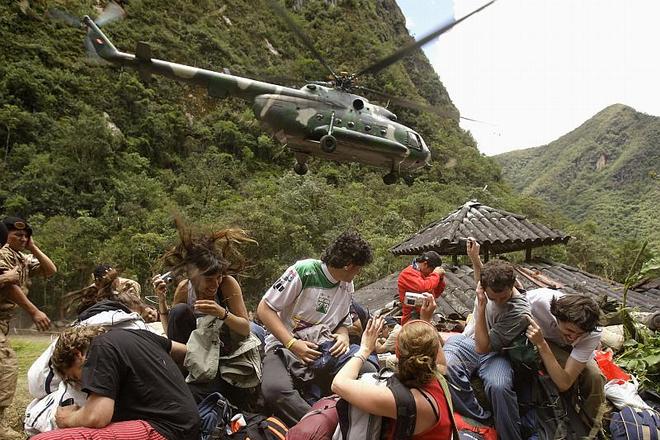Evacuees angle for a good shot while dodging their rescue helicopter's downdraft