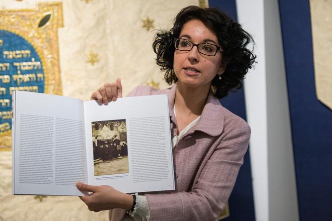 Curator Jana Švantnerová showing a historical photo in the catalogue. 