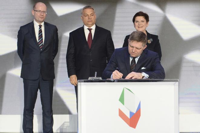 Slovakia's Prime Minister Robert Fico signs the Warsaw Declaration, as his counterparts from Czech Republic, Bohuslav Sobotka (l), Hungary, Viktor Orbán (center), and Poland, Beata Szydlo (r), watch behind.