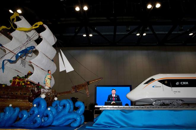 Chinese President Xi Jinping speaking at the opening of the Belt and Road Forum is displayed on a big screen near decorations depicting a modern high speed train and Chinese Admiral Zheng, who commanded expeditionary voyages across Asia and East Africa in the 15th century, in Beijing on May 14. 