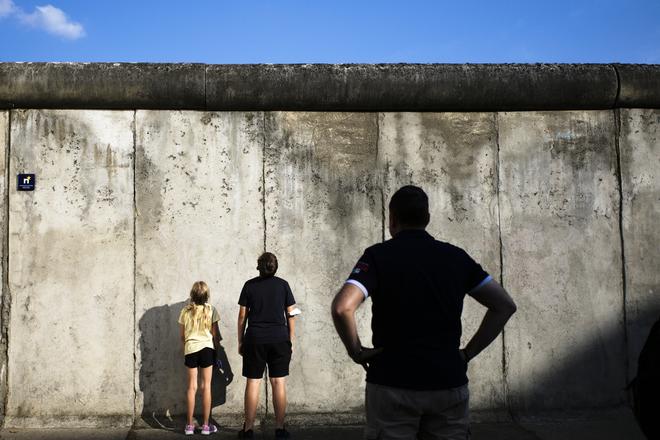 Visitors stand in front of the remains of the Berlin Wall on a street in Berlin on August 12, 2021. 