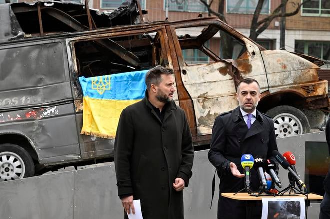 Bratislava Mayor Matúš Vallo (l) and Ukrainian Ambassador to Slovakia Myroslav Kastran stand in front of a destroyed Ukrainian ambulance in downtown Bratislava on 15 April 2025.