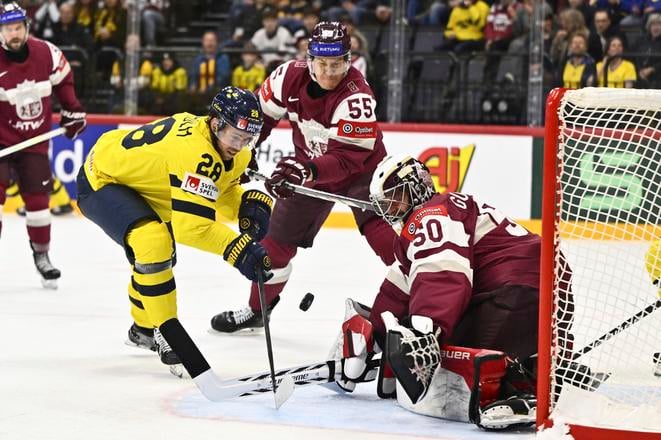 Elias Lindholm pred lotyšským brankárom Gudlevskisom. Anders Wiklund/TT News Agency via AP