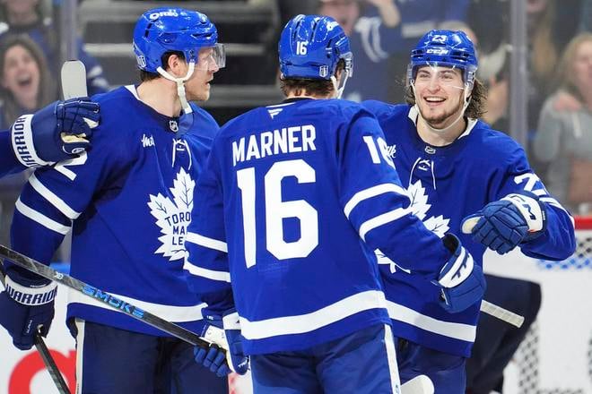Hráč Toronto Maple Leafs Mitch Marner (uprostred) oslavuje so spoluhráčmi Jakeom McCabeom (vľavo) a Matthewom Kniesom (23).