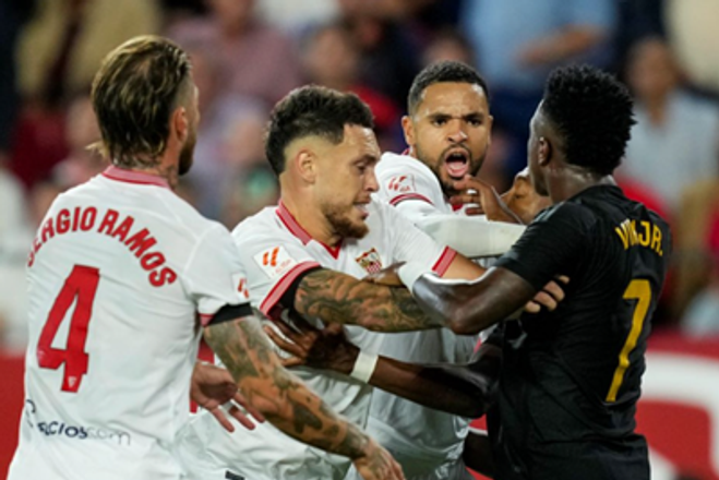 Vinicius Junior z Realu Madrid, vpravo, sa háda s hráčmi Sevilly počas futbalového zápasu španielskej La Ligy.