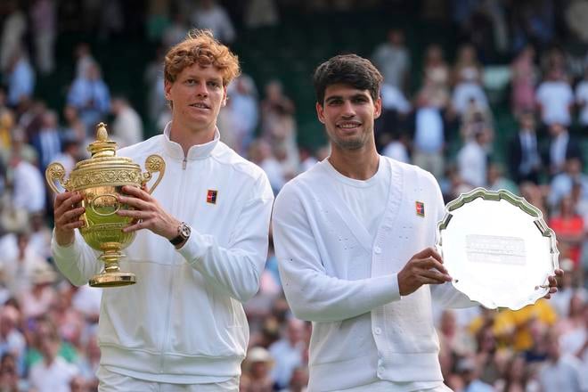 Taliansky tenista Jannik Sinner (vľavo) pózuje s trofejou po víťazstve nad Španielom Carlosom Alcarazom (vpravo) vo finále mužskej dvojhry na grandslamovom turnaji vo Wimbledone.